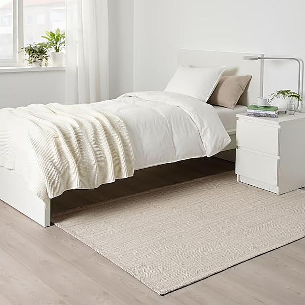 Imagen principal - La alfombra beige en fibra natural cuesta 10 euros en IKEA, las cortinas blancas semitransparentes cuestan 12 euros y el espejo de pared, 19 euros.