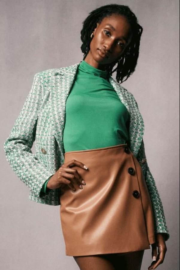 Americana de tejido de rizo verde (35 euros) y minifalda de piel sintética cámel (18 euros).