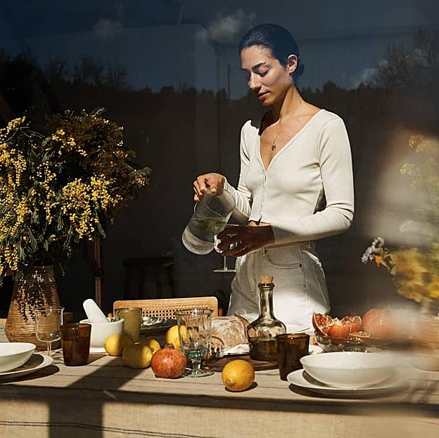 Imagen principal - El mantel de lino de rayas cuesta 59.99 euros, los vasos y copas, desde 4.99 euros, las jarras de cerámica 29.99 euros y la silla de madera, 99.99 euros en Zara Home. Las cestas de madera cuestan 29.99 euros, los jarrones están disponibles desde 29.99, las mantas de lana rizada 99 euros y la alfombra, 599 euros.