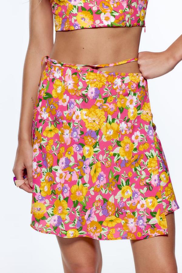 Tiro alto y cierre lateral con lazada para esta minifalda de fondo rosa con estampado de flores en tonos morados y amarillos que cuesta 19,95 euros y podemos encontrar en Zara. 
