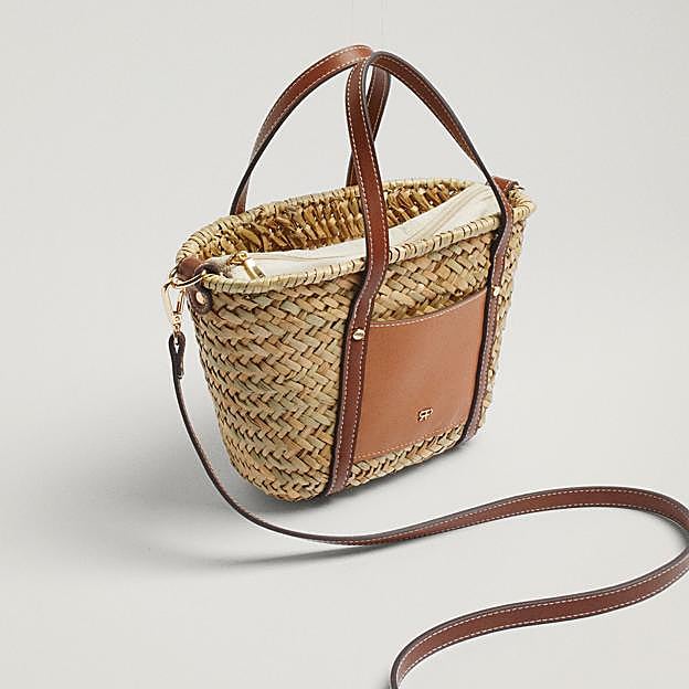Imagen principal - Los diseños confeccionados en tejidos naturales, como la rafia, el yute, la palma, son un auténtico básico cuando suben las temperaturas. Bolso de rafia estilo cesta con asas efecto piel de Parfois (27,99 euros)