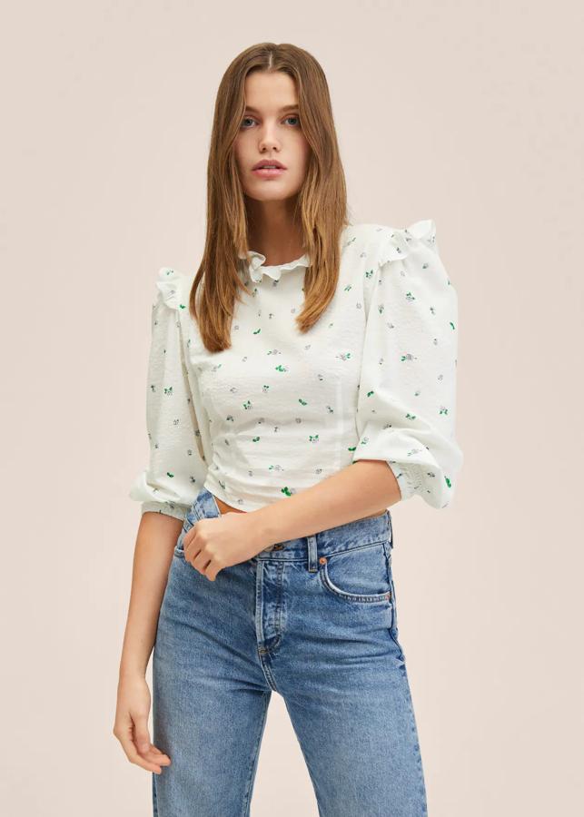 En tejido fluido de mezcla de algodón, con detalle de volantes en el cuello y mangas largas abullonadas con elásticos en las mangas, esta blusa blanca de Mango tiene un precio de 29,99 euros. 