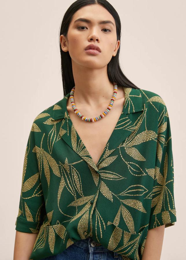 Fondo verde oscuro y estampado de hojas en beige para esta blusa fluida de Mango en diseño oversize, con cuello camisero y mangas cortas. Tiene un precio de 25,99 euros. 