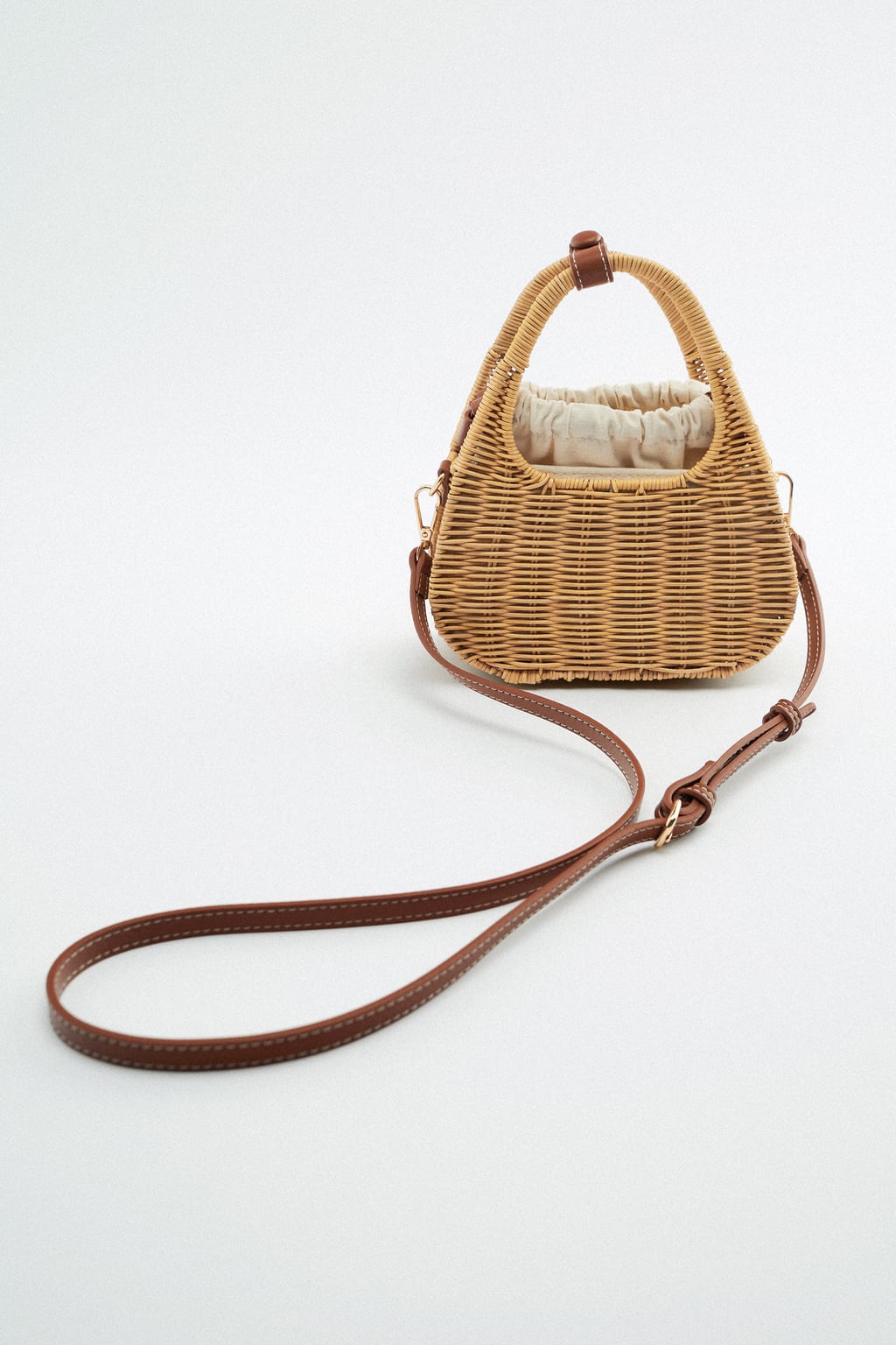 Aunque este tipo de bolsos son perfectos para llevarlos en la mano, siempre viene bien tener un plan b. Una simple asa larga nos permitará llevarlos en bandolera y ganar comodidas. Bolso de ratán de Zara (29,99 euros): 