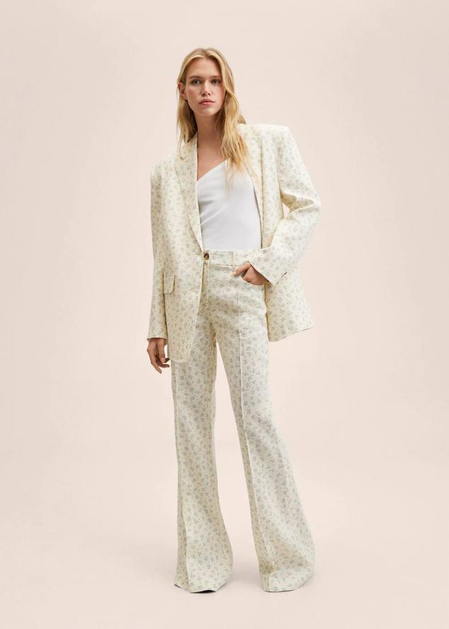 Traje de Mango confeccionado en tejido de lino con estampado floral en crudo y azul claro. Se compone de americana oversize de estilo masculino y pantalón de tiro alto con pierna recta y ancha y detalle de raya marcada. El precio de las prendas es de 79,99 euros y 49,99 euros, respectivamente.