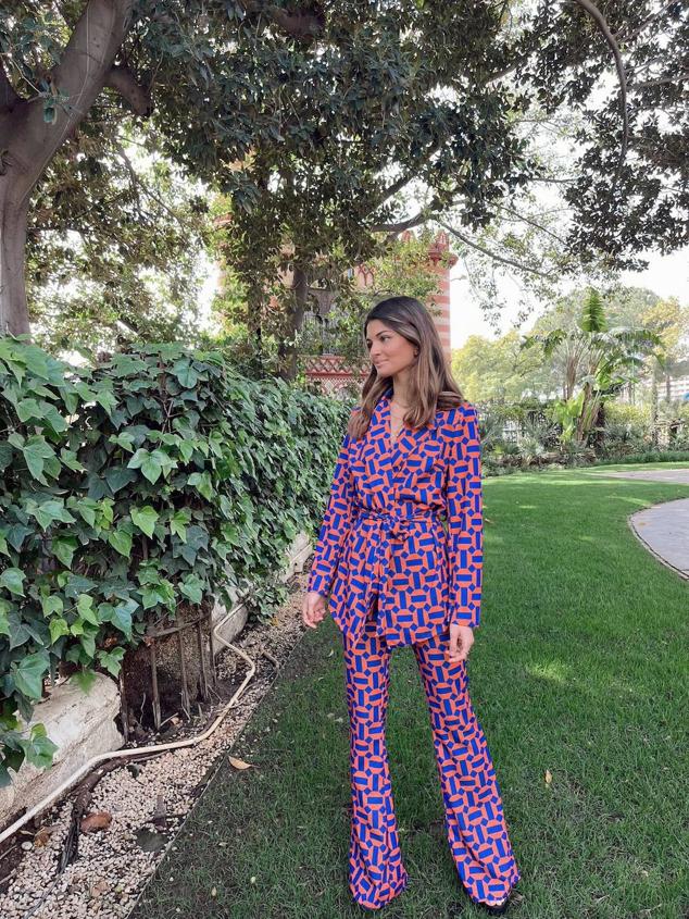 Traje de Elephant Rooms con estampado geométrico en azul y rojo. El conjunto cuenta con blazer cruzada de cuello solapa y cinturón de lazada, más un pantalón fluido y acampanada. Tiene un coste de 42,90 euros.