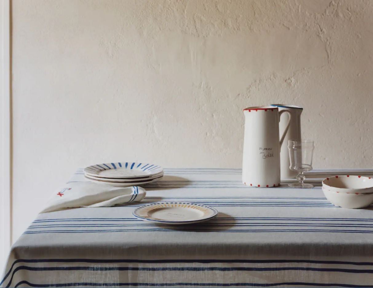 La mesa es, sin duda, el epicentro de la cultura mediterránea. Por eso, la colección de Picasso x Zara Home nos deja una línea de menaje irresistible, con manteles como este de lino con estampado de rayas (79.99 euros) o las jarras de loza pintadas (49.99 euros). 