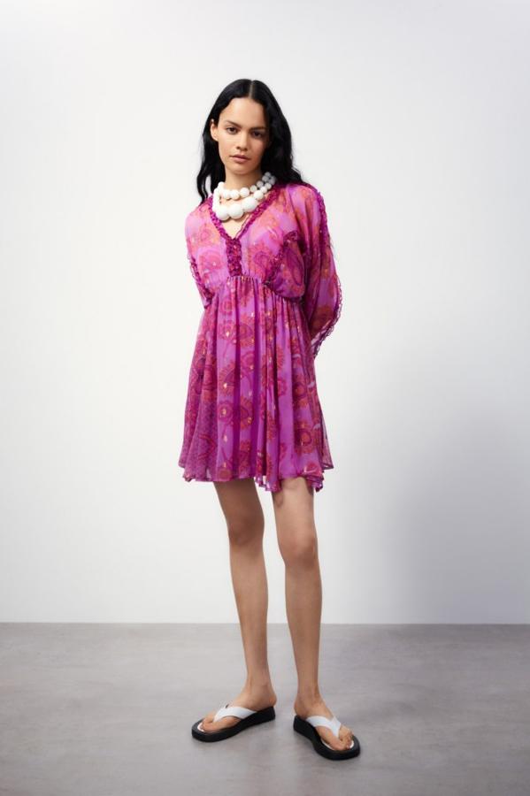 Fondo en color berenjena y estampado retro en tonos rojos para este vestido corto confeccionado en tejido vaporoso que tiene mangas largas, escote de pico y volantes en las mangas y el cuerpo. Es de Sfera y tiene un precio de 35,99 euros. 