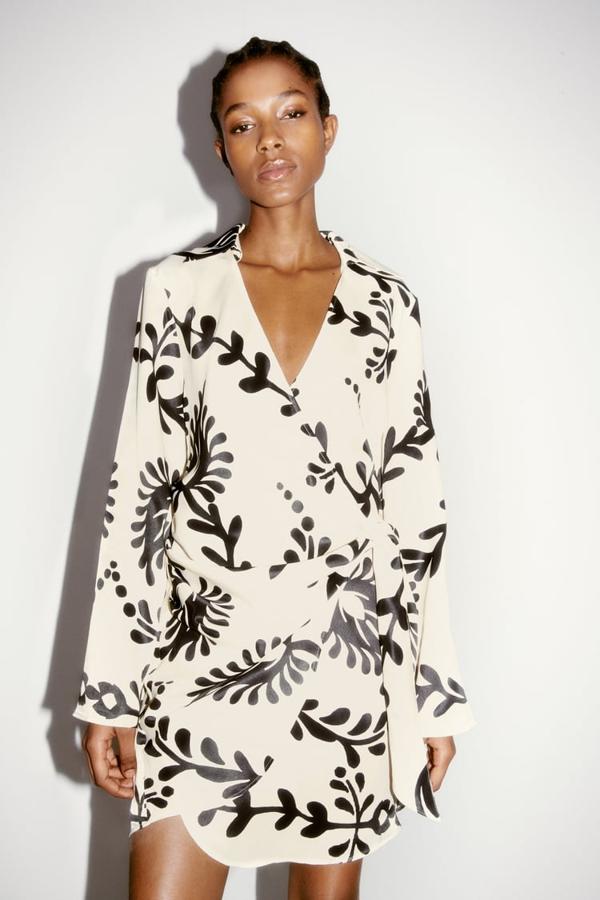 Con cuello de solapa y escote de pico, este vestido blanco con estampado en negro de Zara que viene con cierre frontal cruzado con lazo cuesta 35,95 euros. 