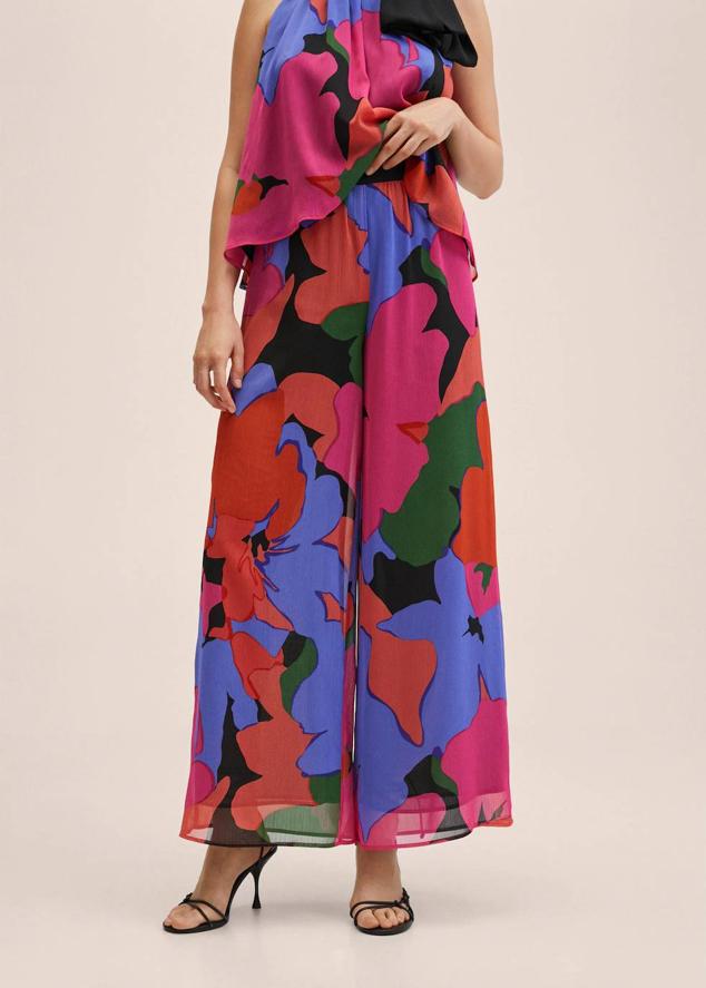Pantalón de estilo palazzo hecho de tejido fluido, ligero y vaporoso que se adorna con maxi estampado multicolor en rojo, rosa, morado, verde y negro. El diseño cuenta con pernera amplia, tiro alto y cierre de cremallera y está ligeramente fruncido en la cintura. Es una prenda de la nueva colección de Mango y tiene un coste de 49,99 euros. A pesar de está de estar disponible entre la XS y la XL, la mayoría de tallas se han agotado y tendrás que apuntarte a la lista de espera.