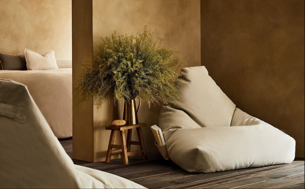 O con una lectura relajada en uno de estos comodísimos puffs de algodón de Zara Home (99 euros).