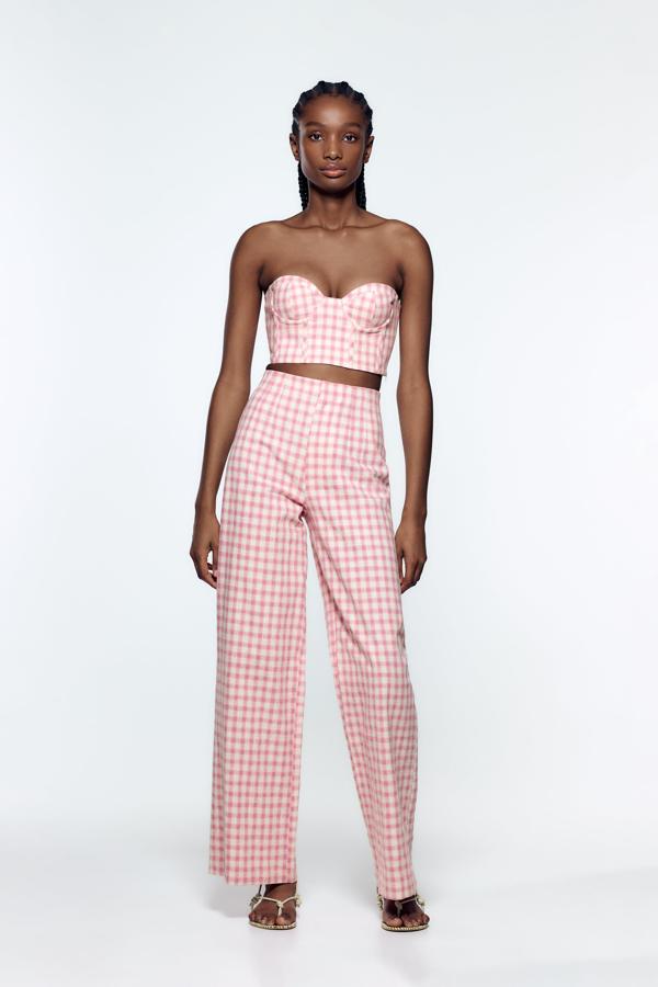 El pantalón más de moda, el llamado wide leg, tampoco podía perderse esta tendencia. En rosa y blanco y combinado con un top tipo bustier para conseguir un look de nota. Pantalón ancho de Zara (19,99 euros) 