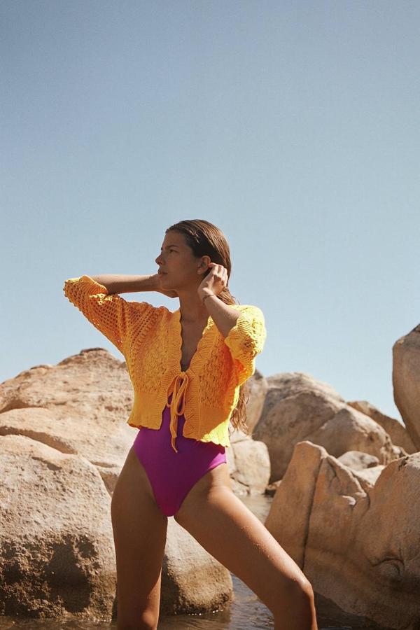 Chaqueta de punto pointelle con diseño abierto, manga por debajo del codo, acabados festoneados y detalle de lazada, color naranja mandarina, de Zara. Tiene un precio de 25,95 euros.