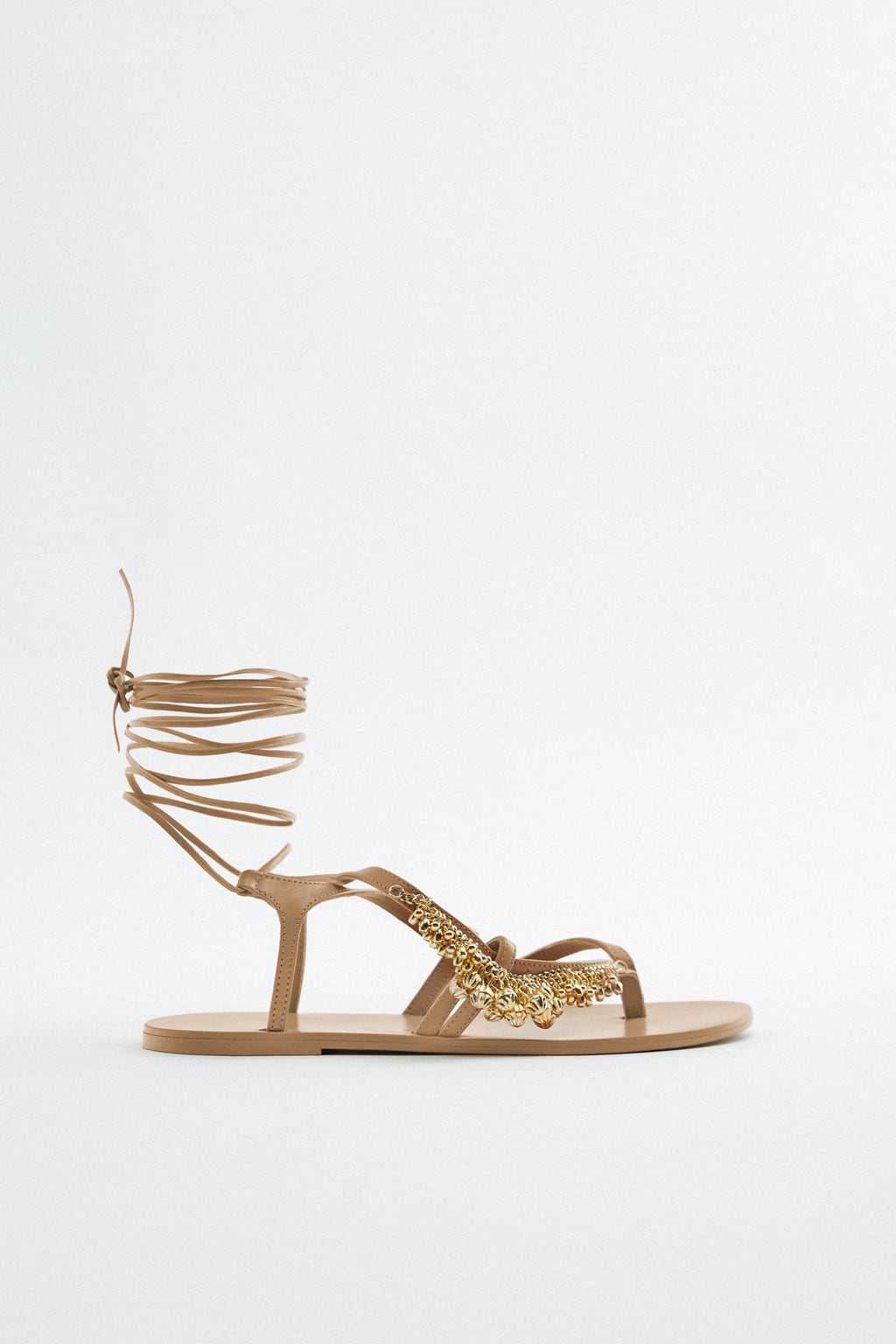 Los tonos metalizados son otra forma de dar un toque elegante a este calzado todoterreno. Elige un diseño que puedas llevar anudado al tobillo y combina el dorado con un color neutro como el beige. Sandalias planas de Zara (59,99 euros)