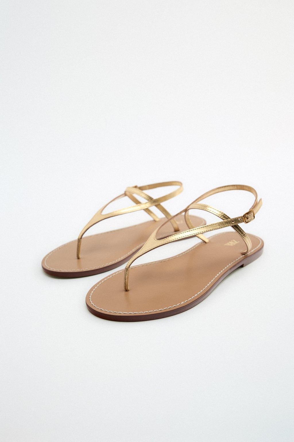 Unas sandalias con un diseño de lo más sencillo pero que te salvarán de cualquier apuro estilístico los próximos meses. Su suave tono dorado combinará con todo tu armario de verano. Sandalias planas de Zara (29,99 euros)