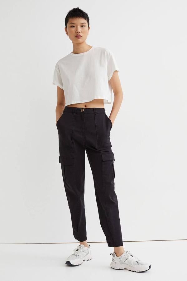 Pantalón cargo en sarga de algodón suave, con pernera pitillo amplia, talle alto, bolsillos al bies y traseros, bolsillos con solapa en la pierna y trabilla ajustable en el bajo, de H&M. Los puedes encontrar en negro y beige claro a 29,99 euros.