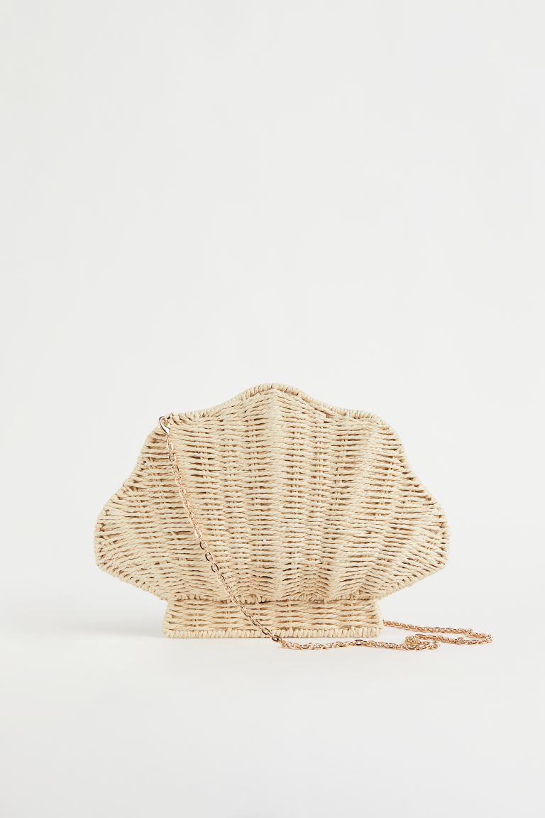 Los bolsos de mano, que llevarás en tus noches de verano, también se cubren de rafia con diseños completamente inesperado. Bolso con forma de concha de H&M (34,99 euros) 