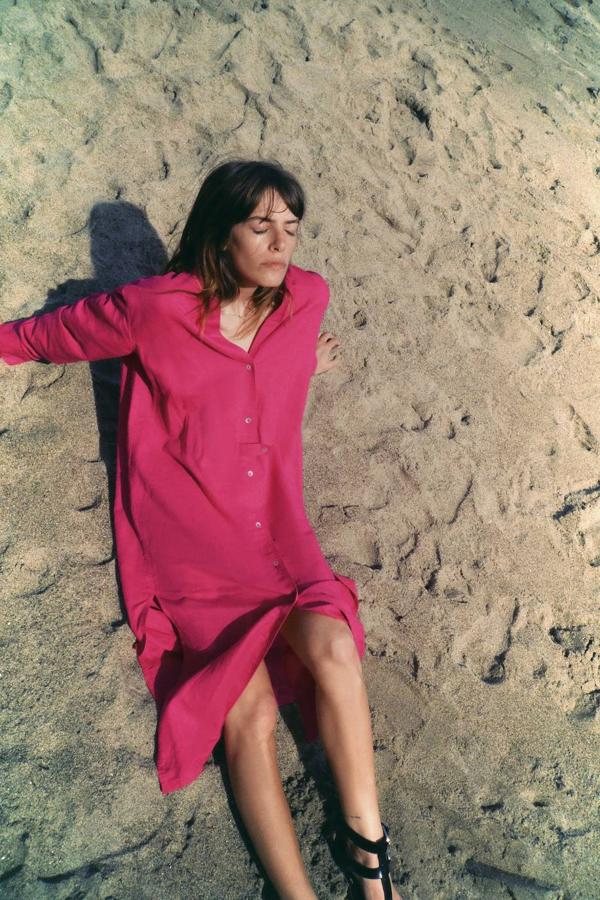 Vestido túnica midi en tejido mezcla de lino, con cuello redondo, manga larga, bajo con aberturas laterales y cierre de botones, color fucsia, de Zara. Lo encontrarás por 19,99 euros.