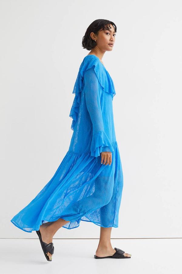 Vestido midi confeccionado en tejido vaporoso texturizado, con silueta relajada, manga larga, detalles de volantes y abertura en la espalda con detalle de lazo, color azul. Lo encontrarás con un precio de 59,99 euros.