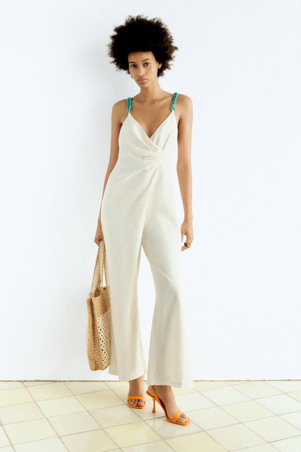 Mono en tejido de lino con escote de pico cruzado, tirantes de cadenas a contraste en turquesa, pernera recta holgada y detalle de fruncidos en el pecho, color blanco, de Zara, Está disponible por 39,95 euros.