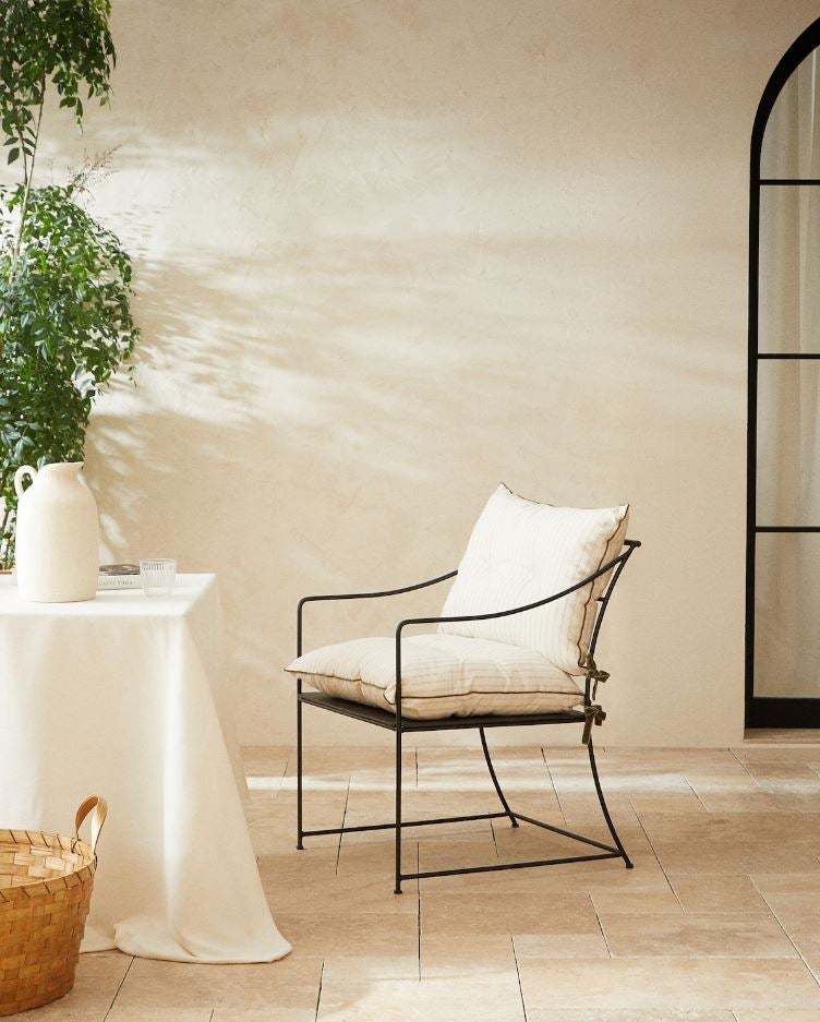 Otra opción elegante y sofisticada, con un toque retro, para los comedores exteriores con más estilo es esta butaca de hierro y aluminio con reposa brazos curvados de Zara Home (249 euros).