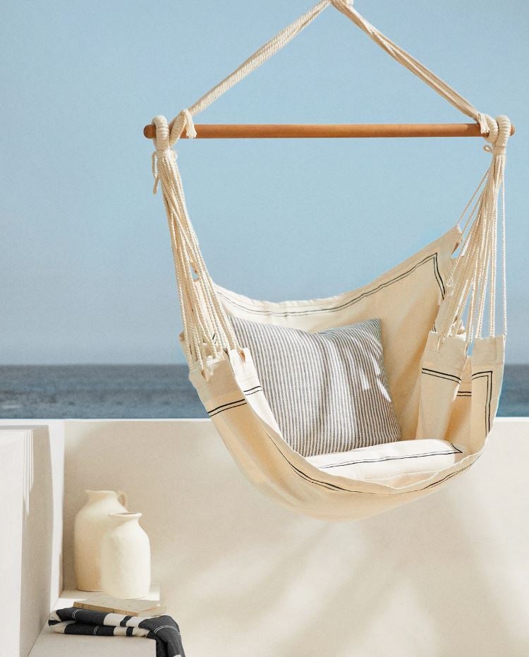Esta silla colgante confeccionada en color natural con rayas a contraste, dos cojines y detalle de cuerdas trenzadas y madera de acacia cuesta 99 euros en Zara Home.