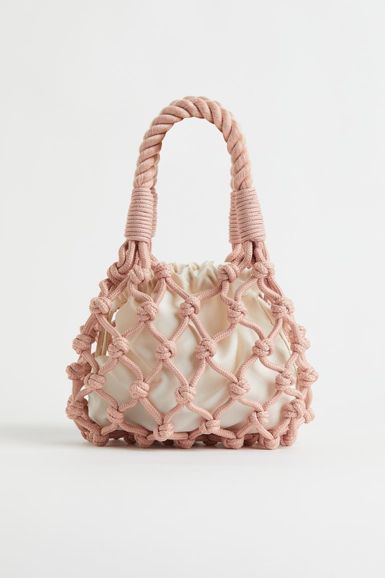 Los bolso de rafia convivien con los diseños trenzados a modo de red. El color rosa pone la nota de color a este original bolso de mano. Bolso en rosa maquillaje de H&M (29,99 euros)