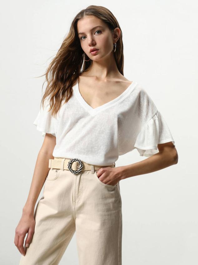 Camiseta efecto lino con cuello de pico, corte holgado y manga corta de volante. Puedes encontrarla en tonos blanco, arena o verde, a 7,99 euros.