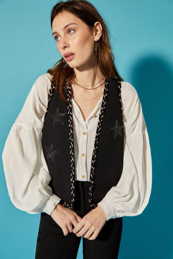 Chaleco abierto con bordados de pedrería en forma de estrellas y acabados en hilo trenzado, color negro. Está rebajado a 39,99 euros.