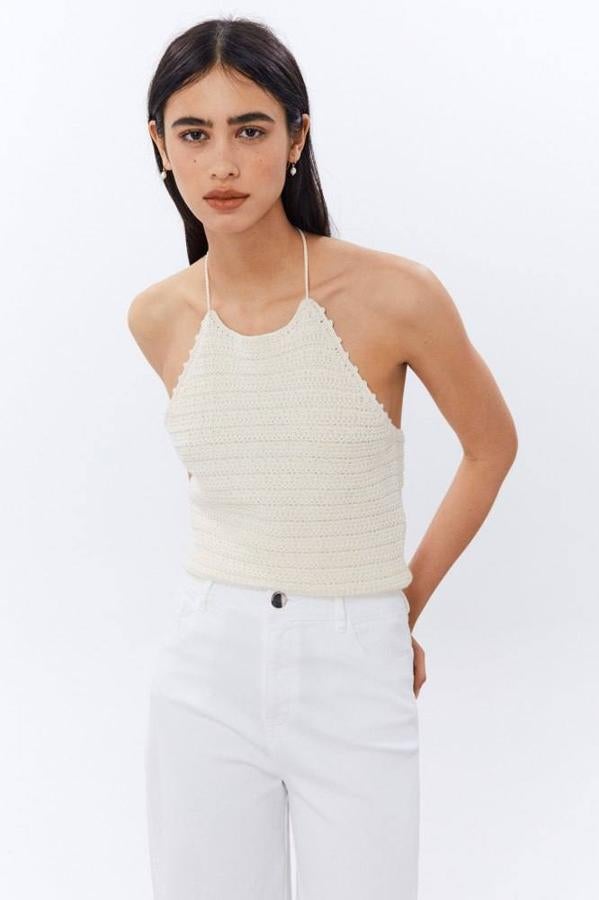 Top de crochet con cuello halter, ajustable por lazada al cuello terminada en borlas y espalda al aire, en tono crema, de Sfera. Lo encontrarás por 15,99 euros.
