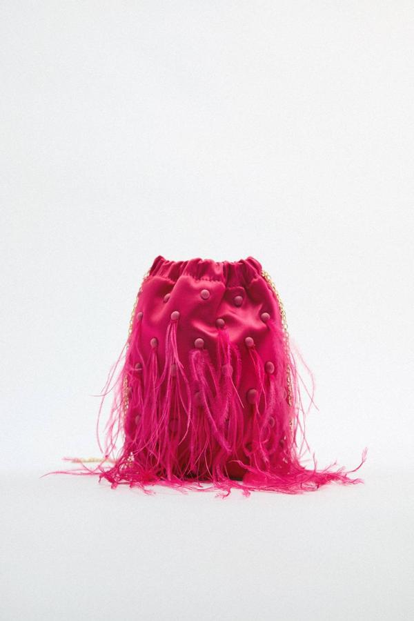 Bolso tipo saca en tejido satinado, de tamaño pequeño, cierre mediante fruncido y asa de cadena para hombro, decorado con adornos de plumas, en fucsia o morado, de Zara. Puedes comprarlo por 35,95 euros.