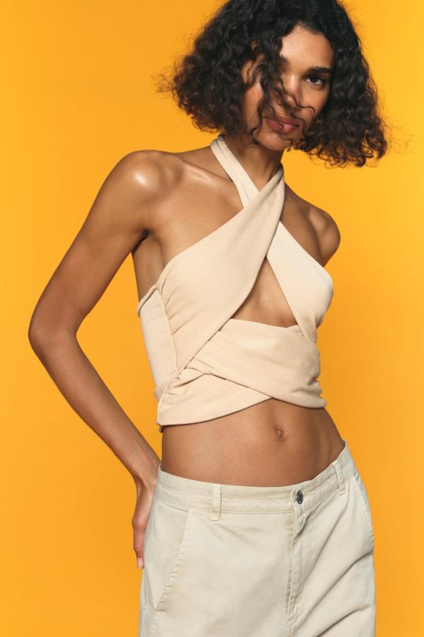 Los tops más sofisticados se presentan con originales escotes cruzados que favorecen a todas las siluetas. Top con escote halter de Zara (15,99 euros)