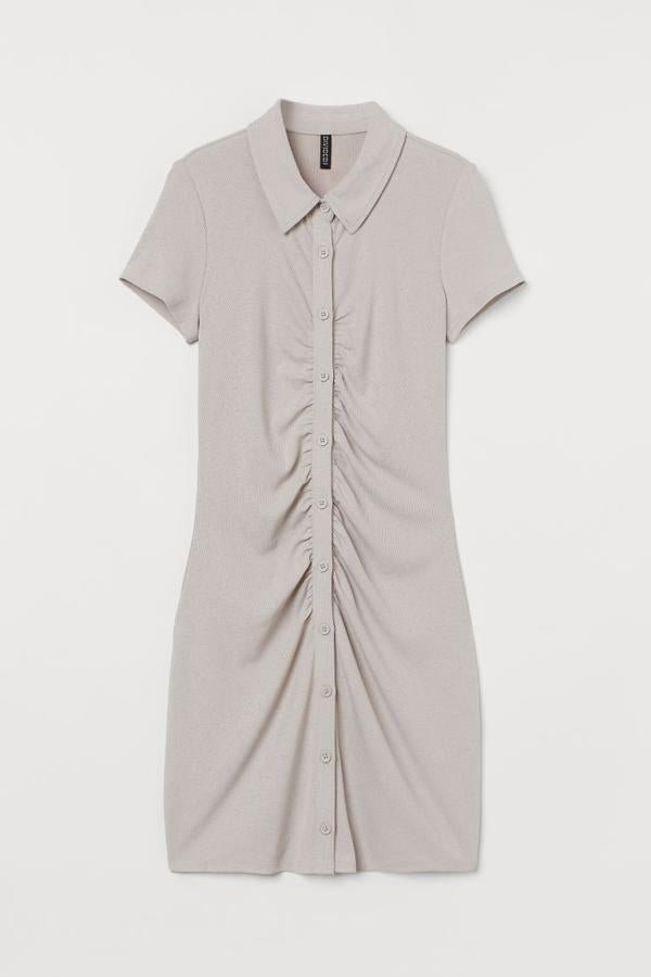 Vestido mini en color gris con botones en la parte central y manga corta. Cuenta con unos fruncidos en la zona de los botones y está disponible en color flúor. Tiene un precio de 7,99 euros.