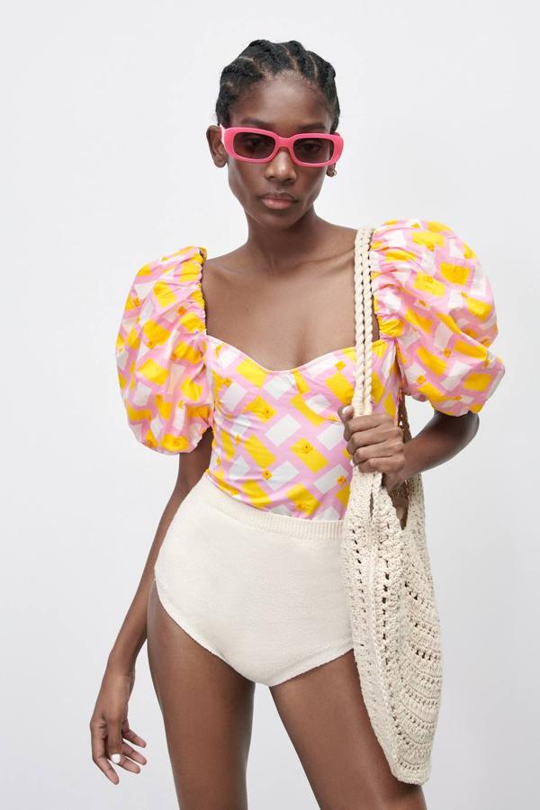 Body de popelín estampado en naranja, rosa y blanco, con escote corazón, manga corta abullonada y tejido elástico en la espalda. Lo encontrarás a 25,95 euros.