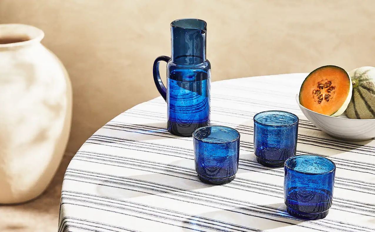 El azul es el color protagonista del verano. El mar, los cielos despejados... y este conjunto de critalería ideal de Zara Home, que antes de las rebajas cuesta 19.99 euros la jarra, 7.99 euros cada vaso, y 59.99 euros el mantel con estampado de rayas.