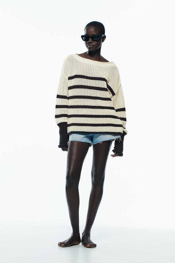 Jersey de punto ligeramente calado oversize con estampado a rayas en crudo y negro, cuello amplio redondo y manga larga acabada en puño a contraste.