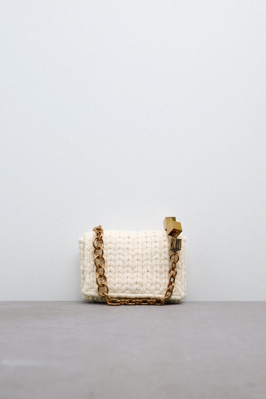 El clásico diseño con cadena y solapa se reinventa con una versión veraniega. Bolso trenzado con cadena dorada de Zara (39,99 euros)