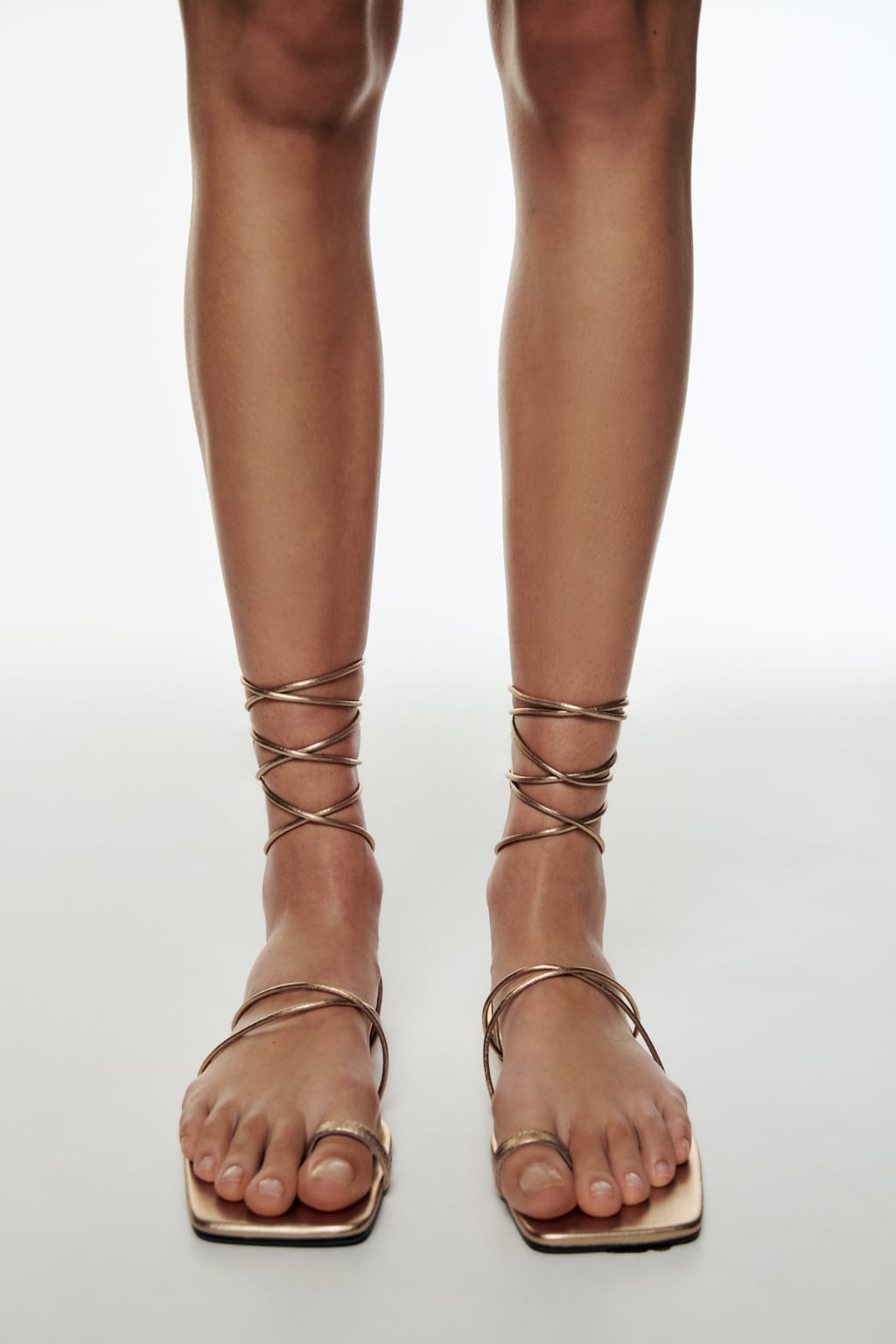 Las sandalias planas son el calzado imprescindible del verano. Elige un diseño dorado, que combina con todo, con tiras anudadas al tobillo. Sandalias de dedo de Zara (49,99 euros) 