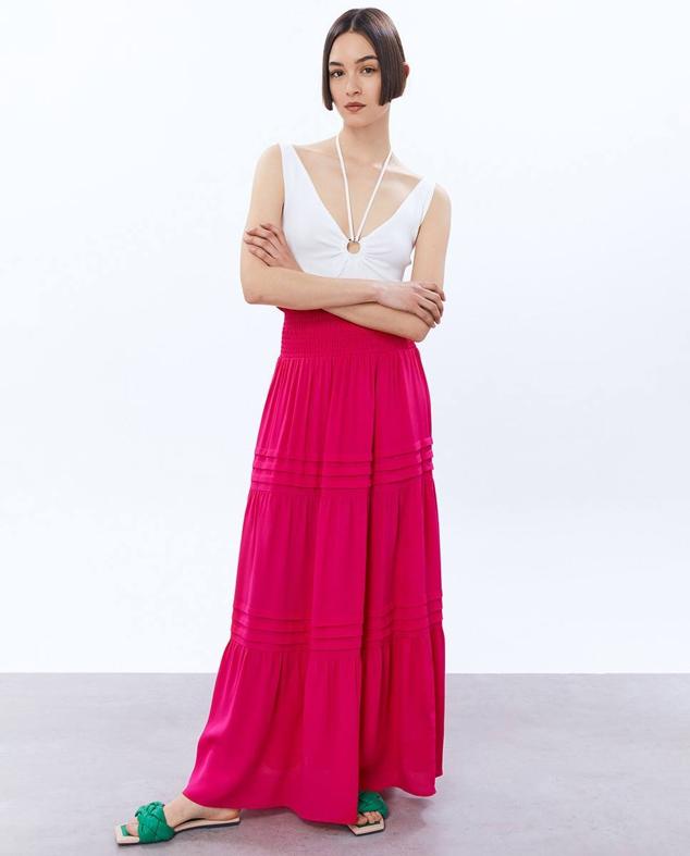 Maxi falda de talle alto con cintura elástica tipo nido de abeja, paneles con detalles plisados y bajo terminado en volante, color fucsia, de Sfera. Puedes comprarla a 25,99 euros.