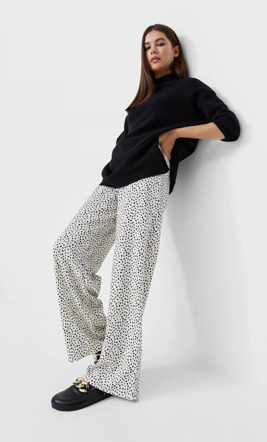 Pantalón largo tipo palazzo en tejido de punto con print de lunares blanco y negro, tiro alto, cintura elástica y pernera ancha, de Stradivarius. Puedes encontrarlo rebajado a 15,99 euros.