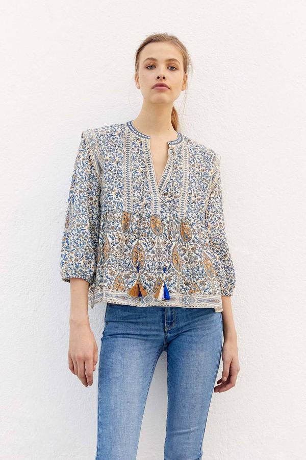 Blusa estilo boho-chic con cuello de pico, manga por debajo del codo terminada en elástico y detalle de cordones con borlas, en estampado floral y paisley. Está disponible rebajada a 15,99 euros.