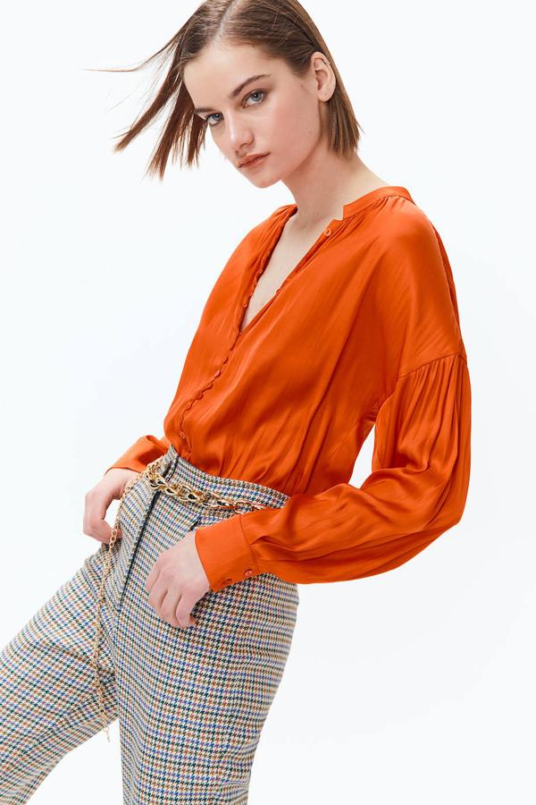 Camisa en tejido satinado con cuello mao, cierre frontal de botones, manga larga termina en puño y silueta relajada, color rojo anaranjado. Puedes comprarla rebajada a 19,99 euros.