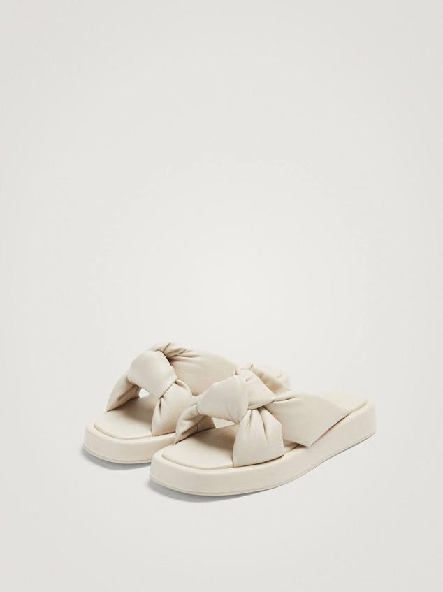 Sandalias planas destalonadas con suela gruesa y tiras acolchadas con nudo, color blanco. Cómpralas rebajas a 29,99 euros.