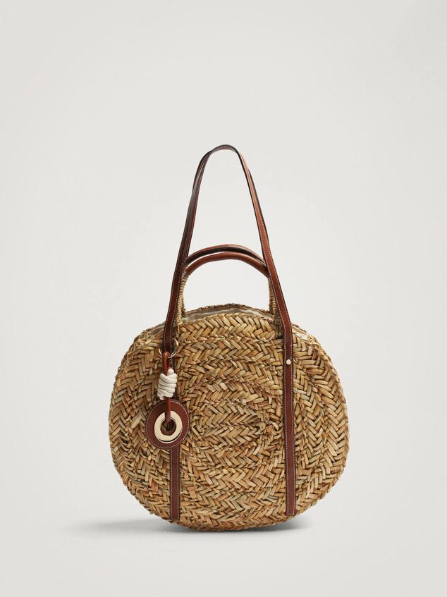 Bolso de paja con diseño circular, doble asa efecto piel y detalle de colgante extraíble, de Parfois. Está disponible con descuento a 25,99 euros. Cómpralo aquí