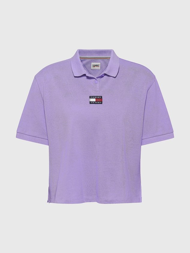 Polo de mujer en color violeta. Lleva el parche de la marca Tommy justo debajo del cuello en la zona del pecho. Está confeccionado de algodón orgánico, con un diseño recto y cuello de polo. Tiene un cierre de dos botones en el cuello. Es de Tommy Jeans. Precio rebajado: 38 €.