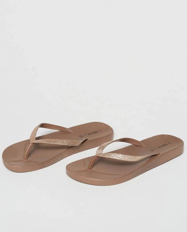 Sfera nos trae estas chanclas de tiras en color beige que cuentan con apliques de purpurina.
