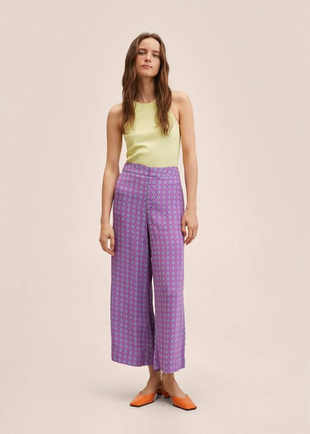 Pantalón en tejido fluido y ligero con tiro alto, cintura elástica, bolsillos laterales y estampado geométrico color lila, de Mango. Cuestan rebajados 19,99 euros.