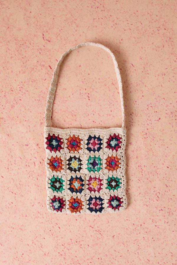 Bolso de crochet con motivos de flores multicolor sobre fondo crudo y asa larga, de Springfield. Podrás comprarlo con descuento por 12,99 euros.