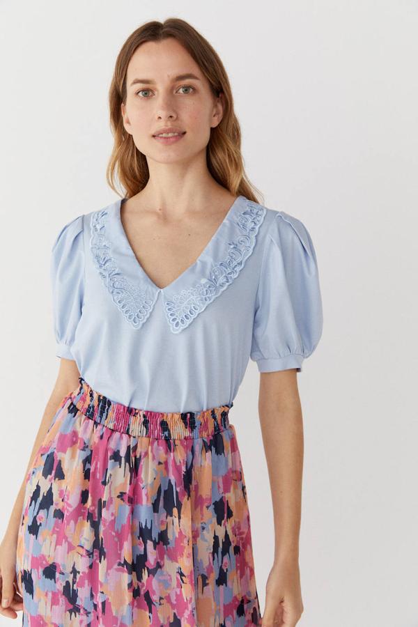 Blusa celeste de manga corta abullonada con escote de pico y cuello bobo bordado, de Cortefiel. Cuesta 20,99 euros con descuento.