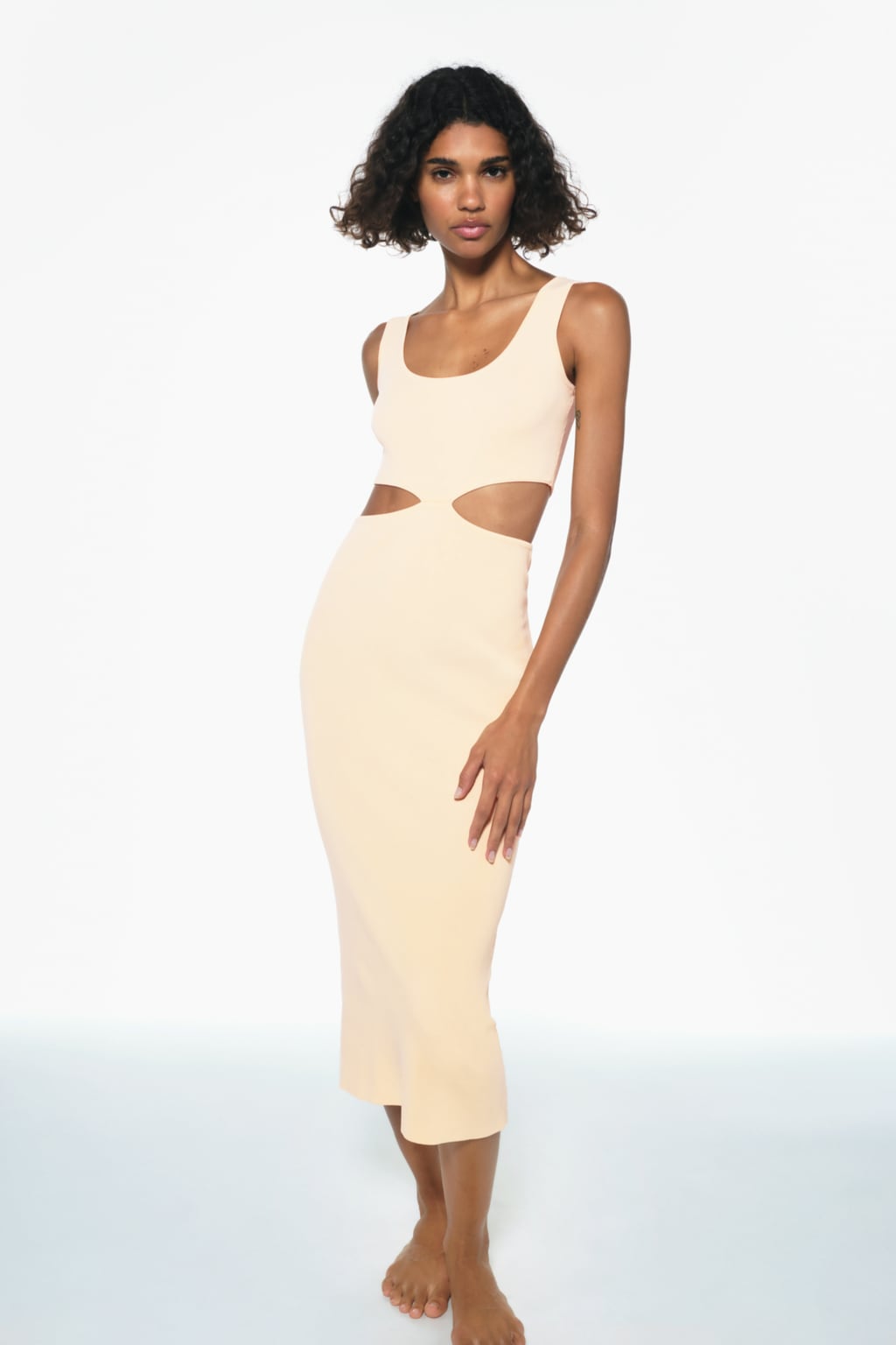Las aberturas estratégicas también se intalan sobre sofisticados vestidos de punto. Vestido midi en color vainilla de Zara (29,99 euros). 
